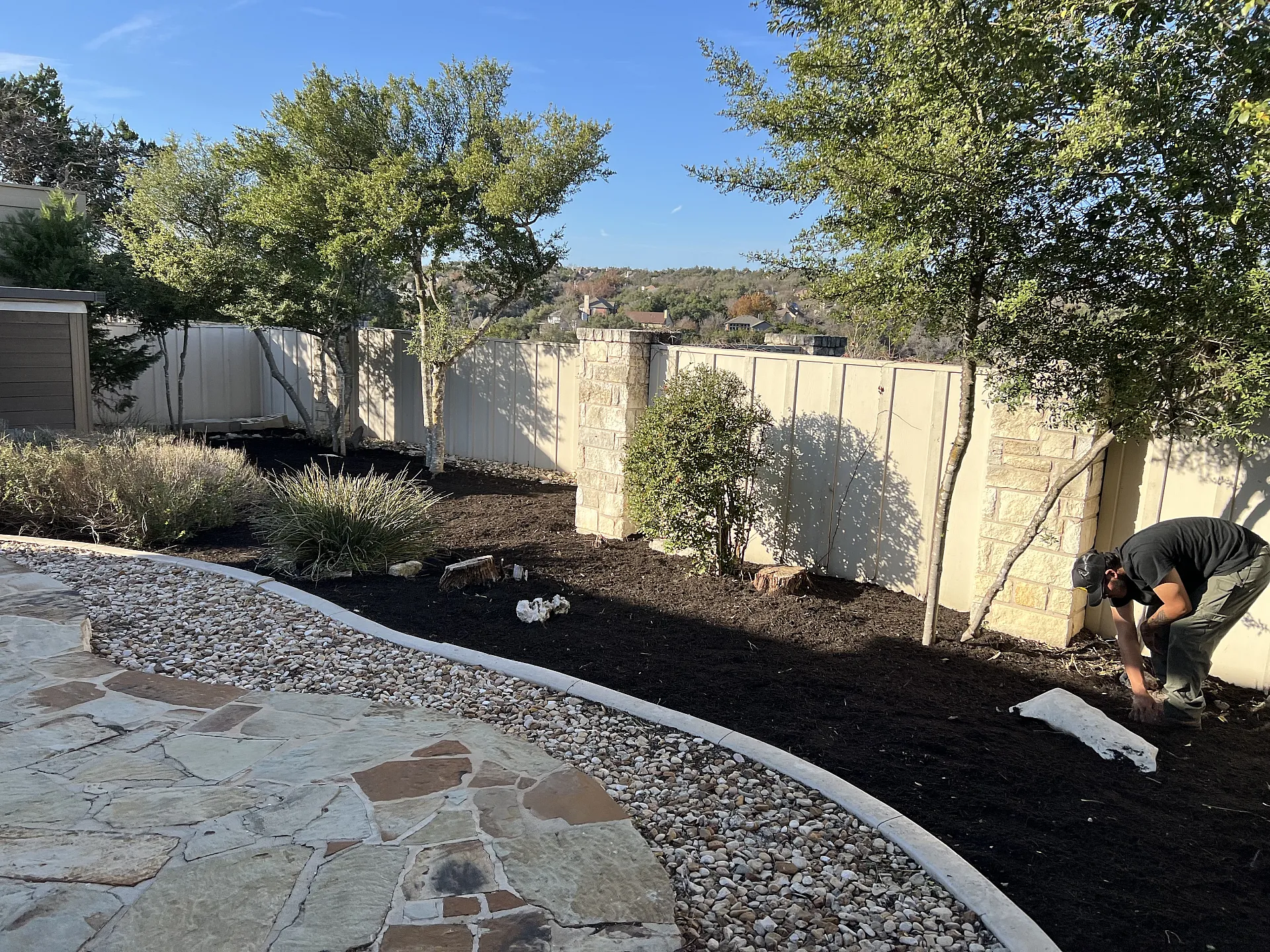 Before: Landscape bed with faded, thin mulch layer and visible weeds.